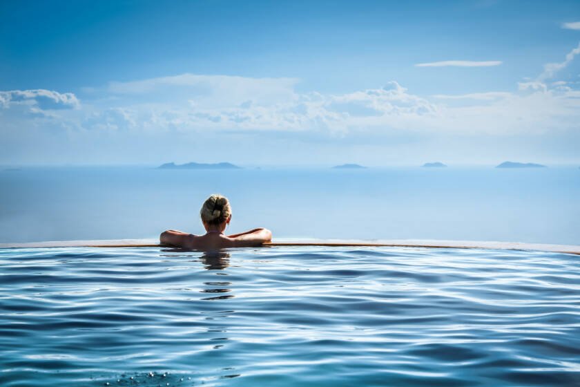 Nature-inspired wellness retreat in Aman resort style with woman in infinity pool