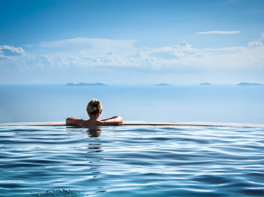 Nature-inspired wellness retreat in Aman resort style with woman in infinity pool